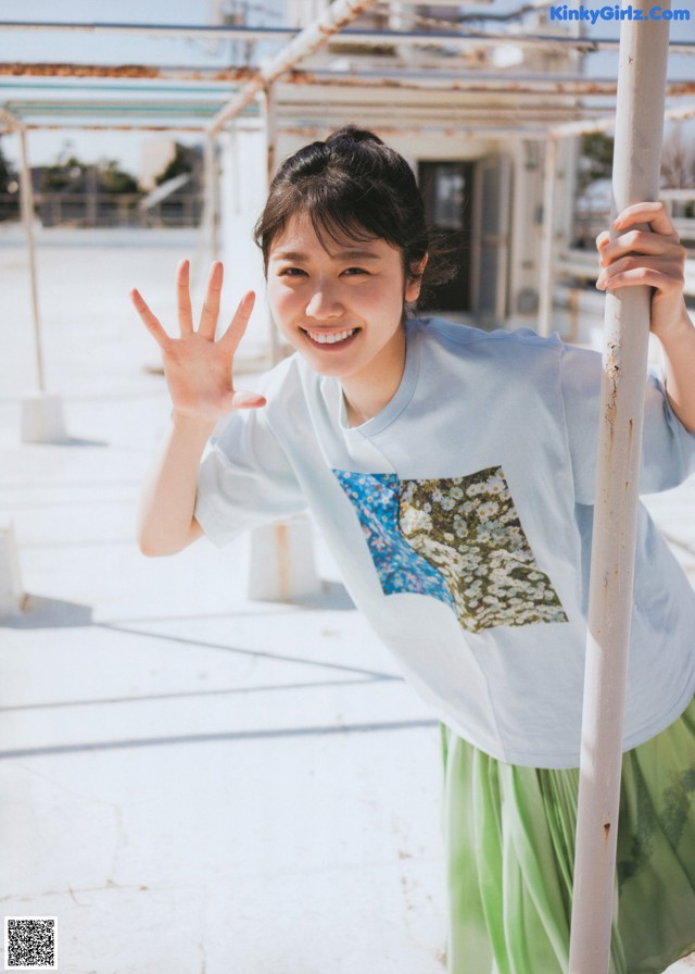 A woman in a blue shirt and green skirt posing for a picture.