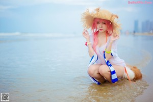 A woman in a straw hat is walking on the beach.