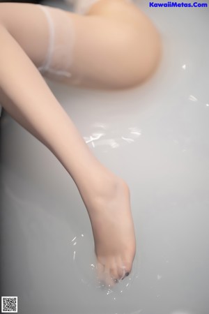 A woman in a bathtub with her feet in the water.