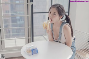 A woman sitting on a wooden floor holding a plate of food.