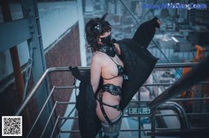 A woman in lingerie holding a gun in a dark room.