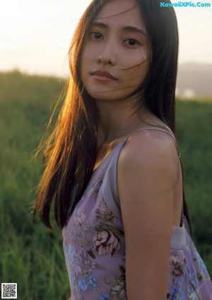 A woman with long brown hair standing in a field.