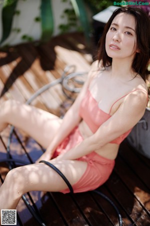 A naked woman sitting on a wooden deck holding a fish bowl.