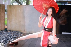 A woman in a red and white outfit holding an apple.