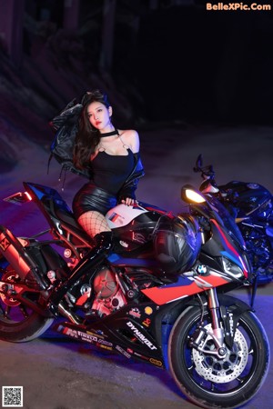 A woman sitting on a motorcycle in a dark room.