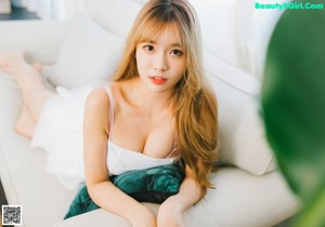 A woman in a white dress sitting on a bed.