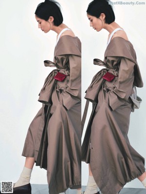 A woman in a beige trench coat and red shoes.
