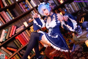 A woman sitting on a stool in front of a book shelf.
