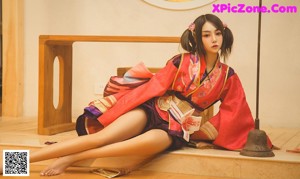 A woman in a red kimono sitting on a wooden bench.