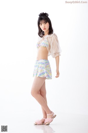 A woman in a bikini top and skirt posing for a picture.