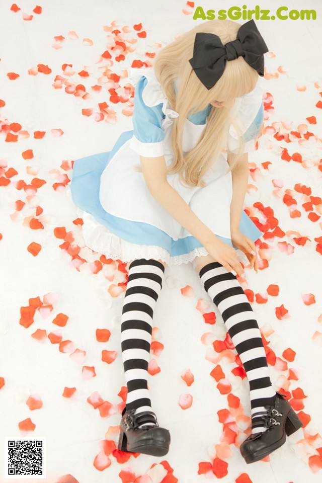 A woman in a blue and white dress sitting on a bed of rose petals.