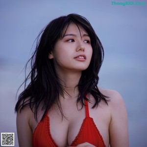 A woman in a bikini leaning against a fence.