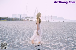 A woman in a white dress standing on a boardwalk.