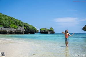 A young woman standing on a beach next to the ocean.