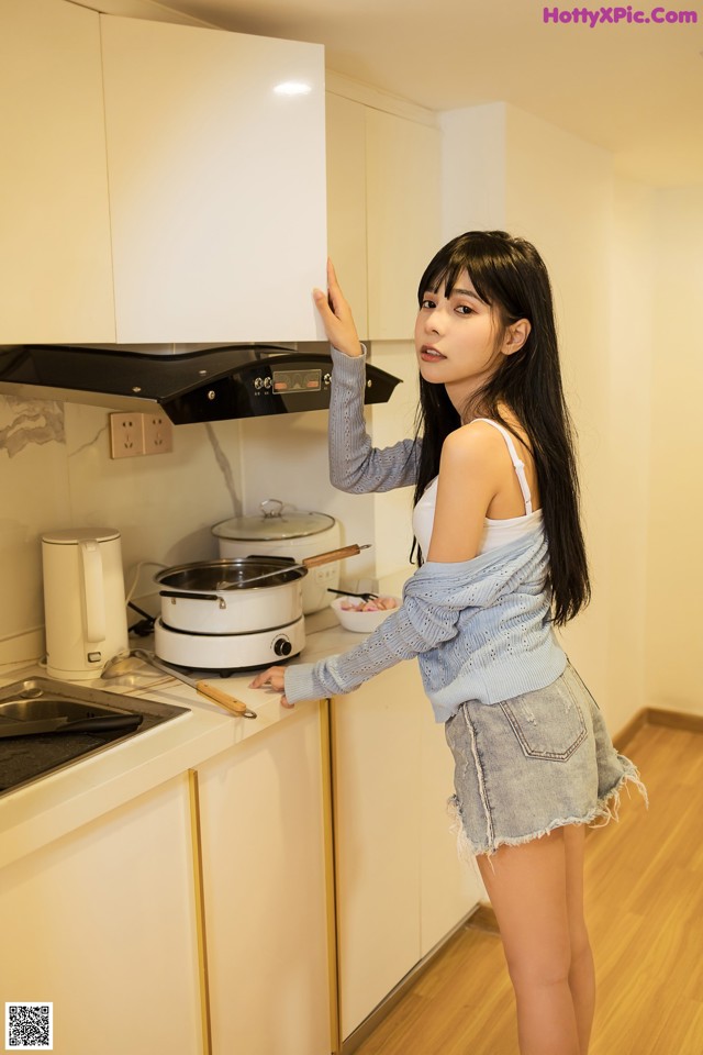 A woman standing in a kitchen next to a stove.