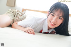 A woman in a school uniform holding a blue bag.