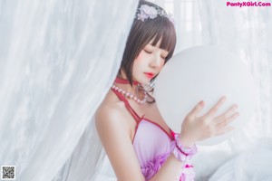 A woman in a pink dress and white stockings laying on a bed.
