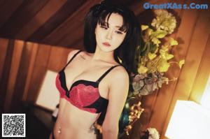 A woman in a black and red lingerie posing for a picture.
